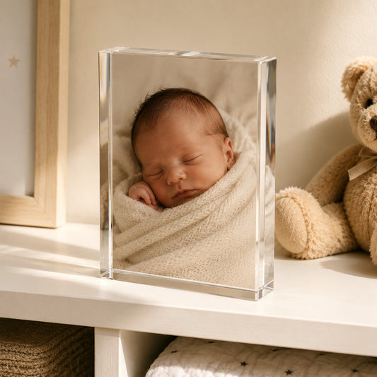 Crystal glass photo block with a sleeping newborn on a shelf beside a teddy bear